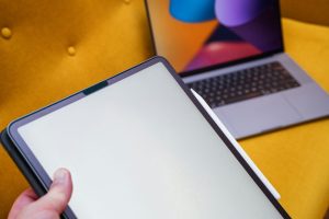 A person holding a tablet in front of a laptop